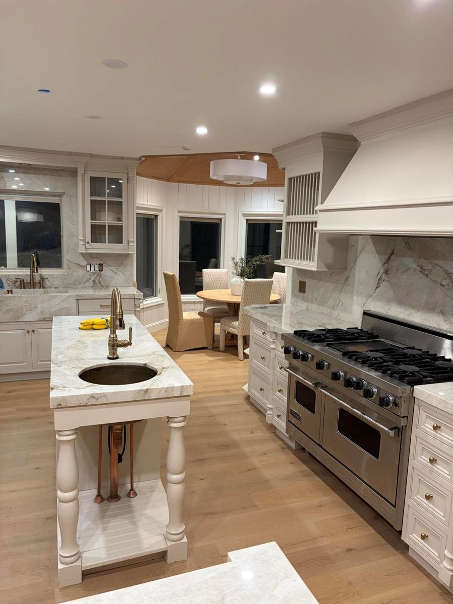 A kitchen with white cabinetry, marble countertops, a central island, and a stainless steel range — 18363 Island Oak Avenue, Jupiter FL 33478, JUPITER, FL