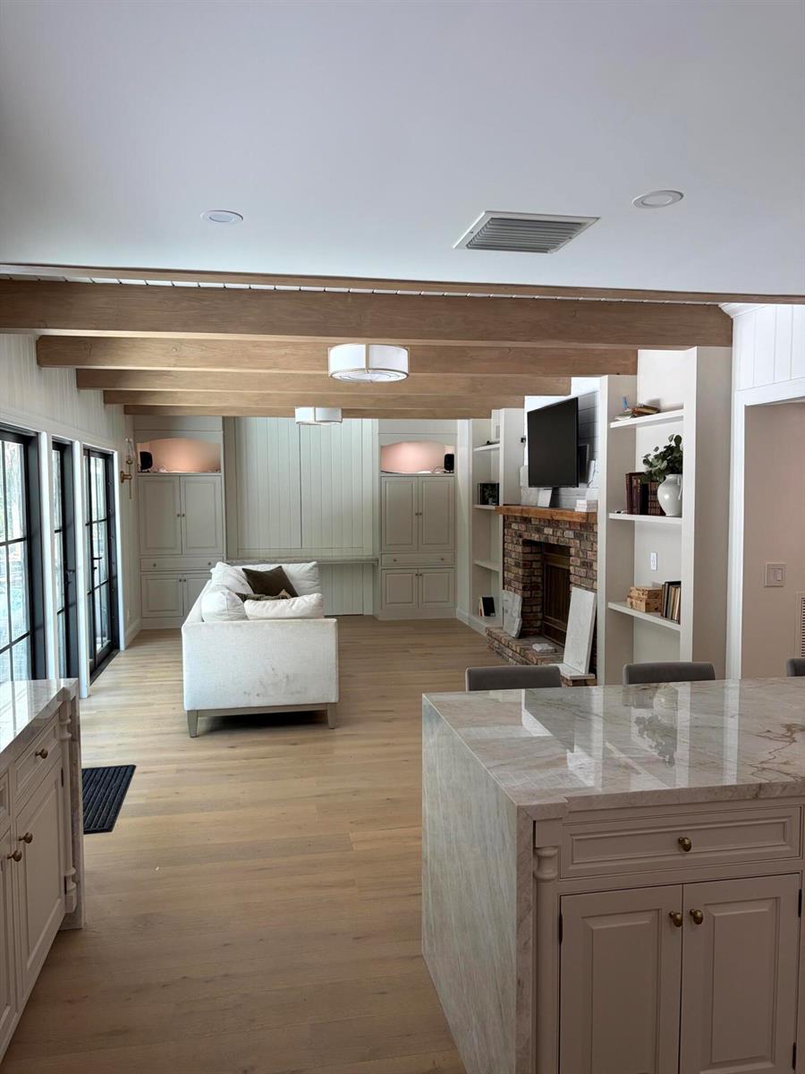 A living room with wooden ceiling beams, a brick fireplace, and built-in white cabinetry — 18363 Island Oak Avenue, Jupiter FL 33478, JUPITER, FL