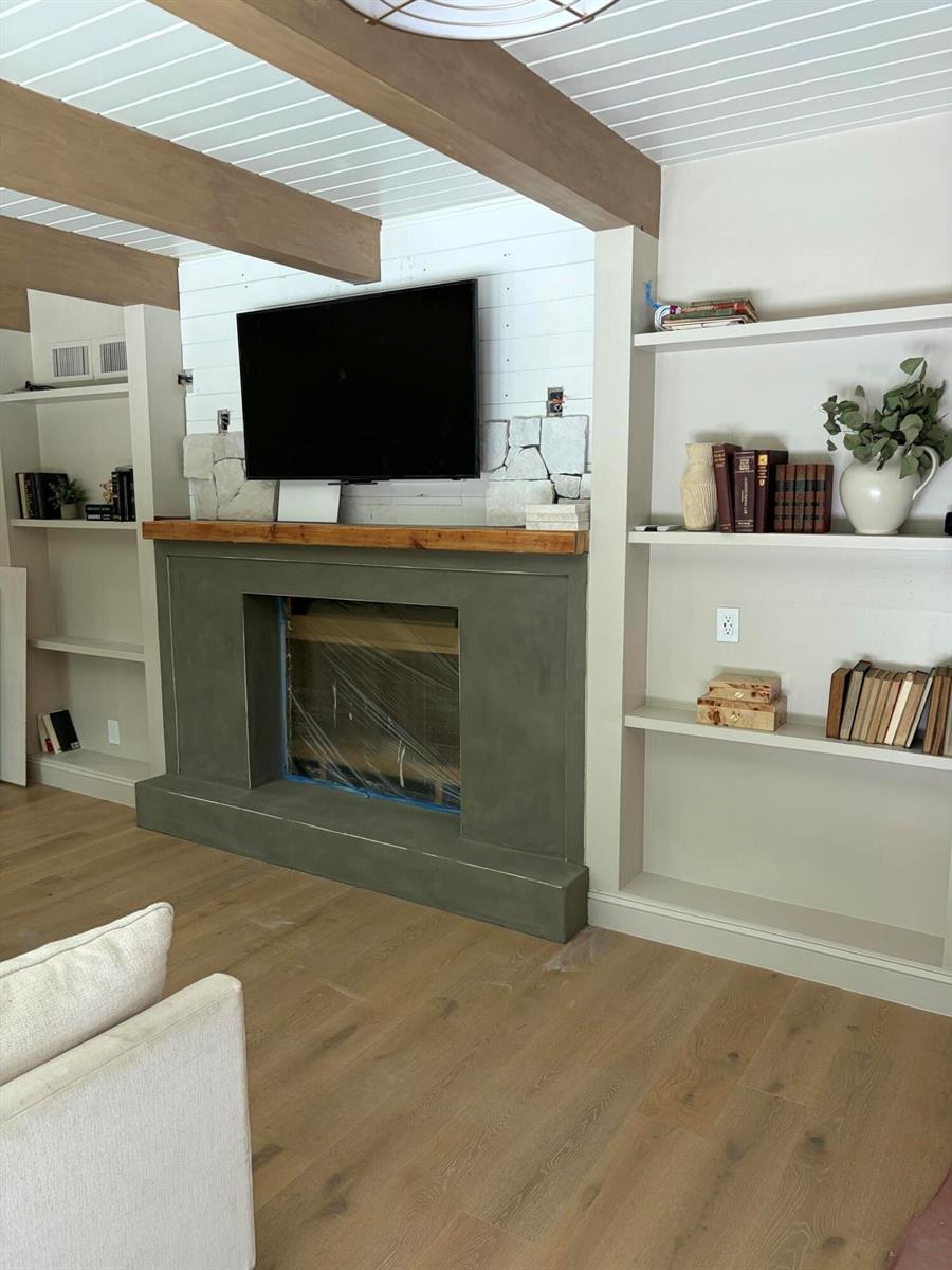 A living room features a fireplace with a concrete surround, wood mantel, and built-in shelving — 18363 Island Oak Avenue, Jupiter FL 33478, JUPITER, FL