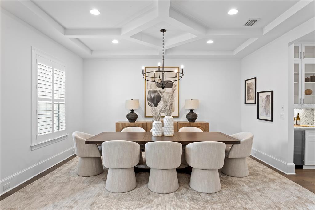 A dining room features a coffered ceiling, a wooden table with six chairs, and a chandelier — 5015 W LONGFELLOW AVENUE, TAMPA, FL
