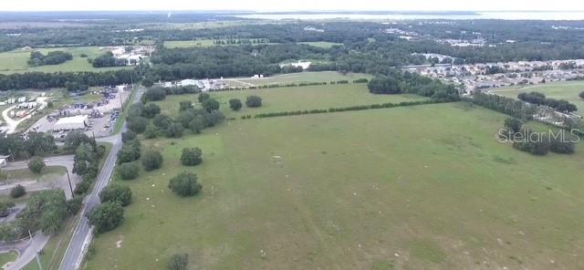 An aerial view shows a large, grassy, undeveloped plot of land near a residential area — HAYWOOD WORM FARM ROAD, LEESBURG, FL