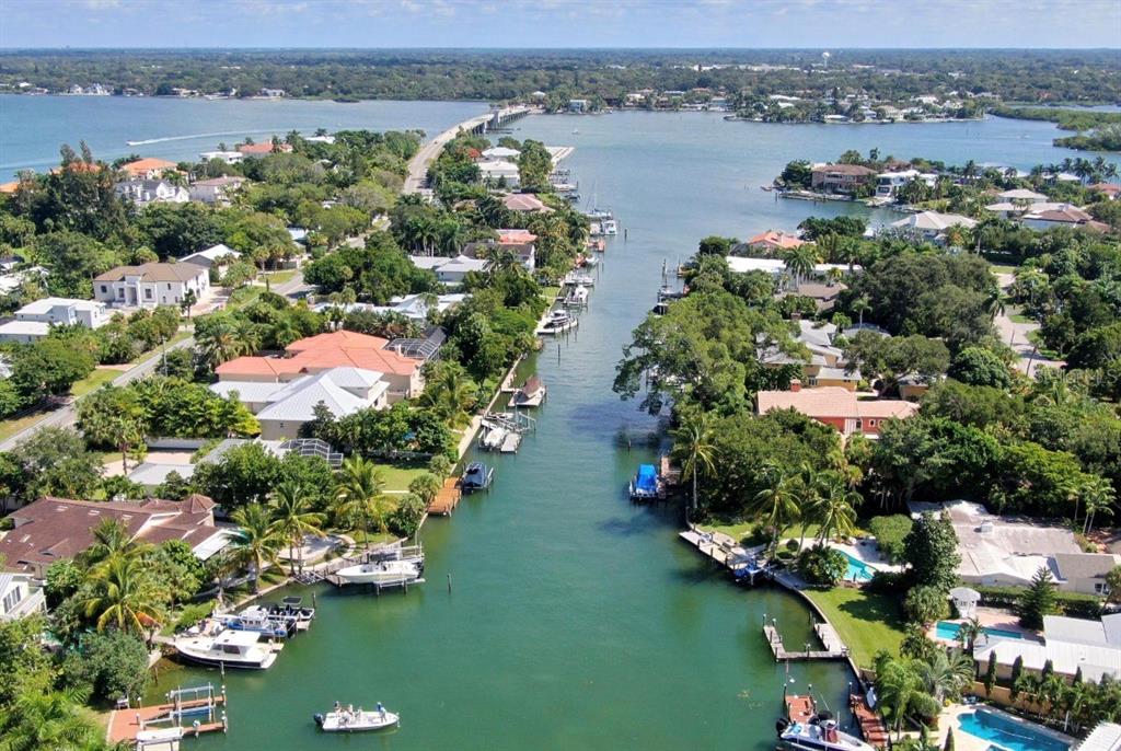 An aerial view shows a residential canal lined with houses, private docks, and docked boats — 749 SIESTA DRIVE, SARASOTA, FL