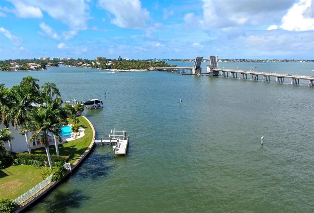 An aerial view shows a waterfront property with a pool, dock, and a drawbridge nearby — 749 SIESTA DRIVE, SARASOTA, FL