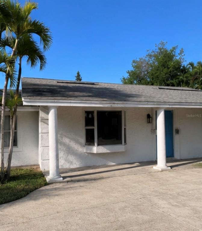 A white house exterior features a covered porch with two columns and a blue door — 749 SIESTA DRIVE, SARASOTA, FL