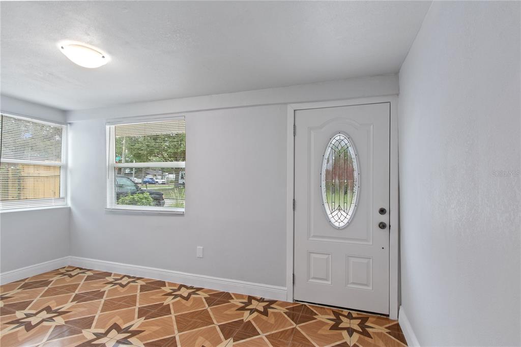 A room with light gray walls, a white front door, and patterned tile flooring — 8514 N MITCHELL AVENUE, TAMPA, FL