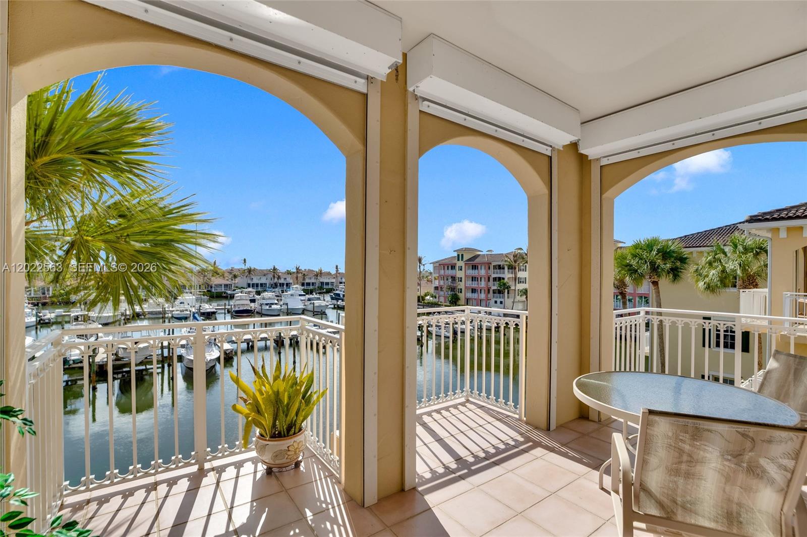 A covered balcony features arched openings, a white metal railing, and views of a marina — VERO BEACH, FL