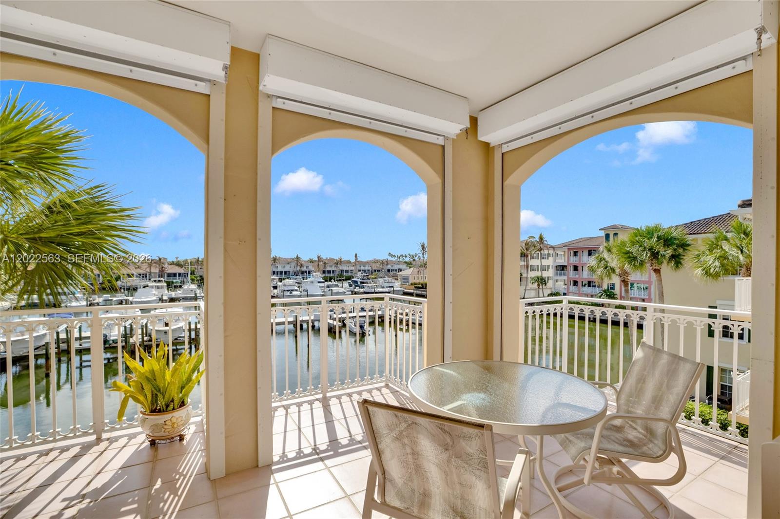 A covered balcony features arched openings, a glass-top table with chairs, and a marina view — VERO BEACH, FL