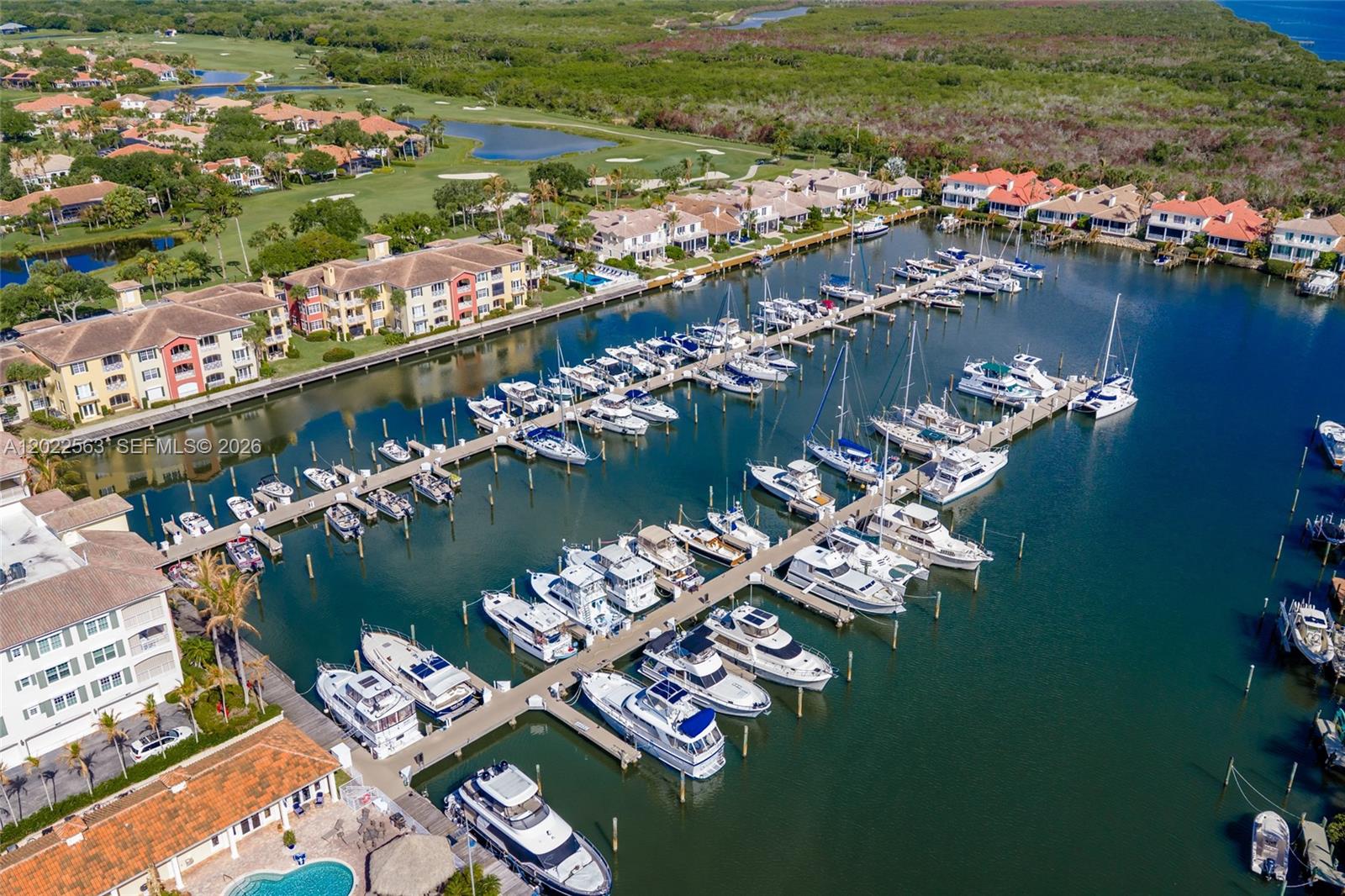 An aerial view shows a marina filled with boats adjacent to residential buildings and greenery — VERO BEACH, FL