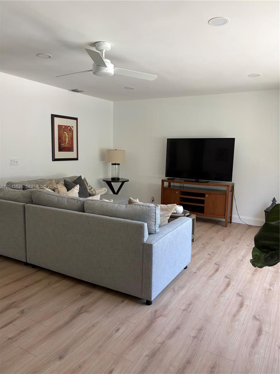 A living room features a gray sectional sofa, a television on a wooden stand, and light-colored wood flooring — 3397 NE 20th Ave, Oakland Park FL 33306, OAKLAND PARK, FL