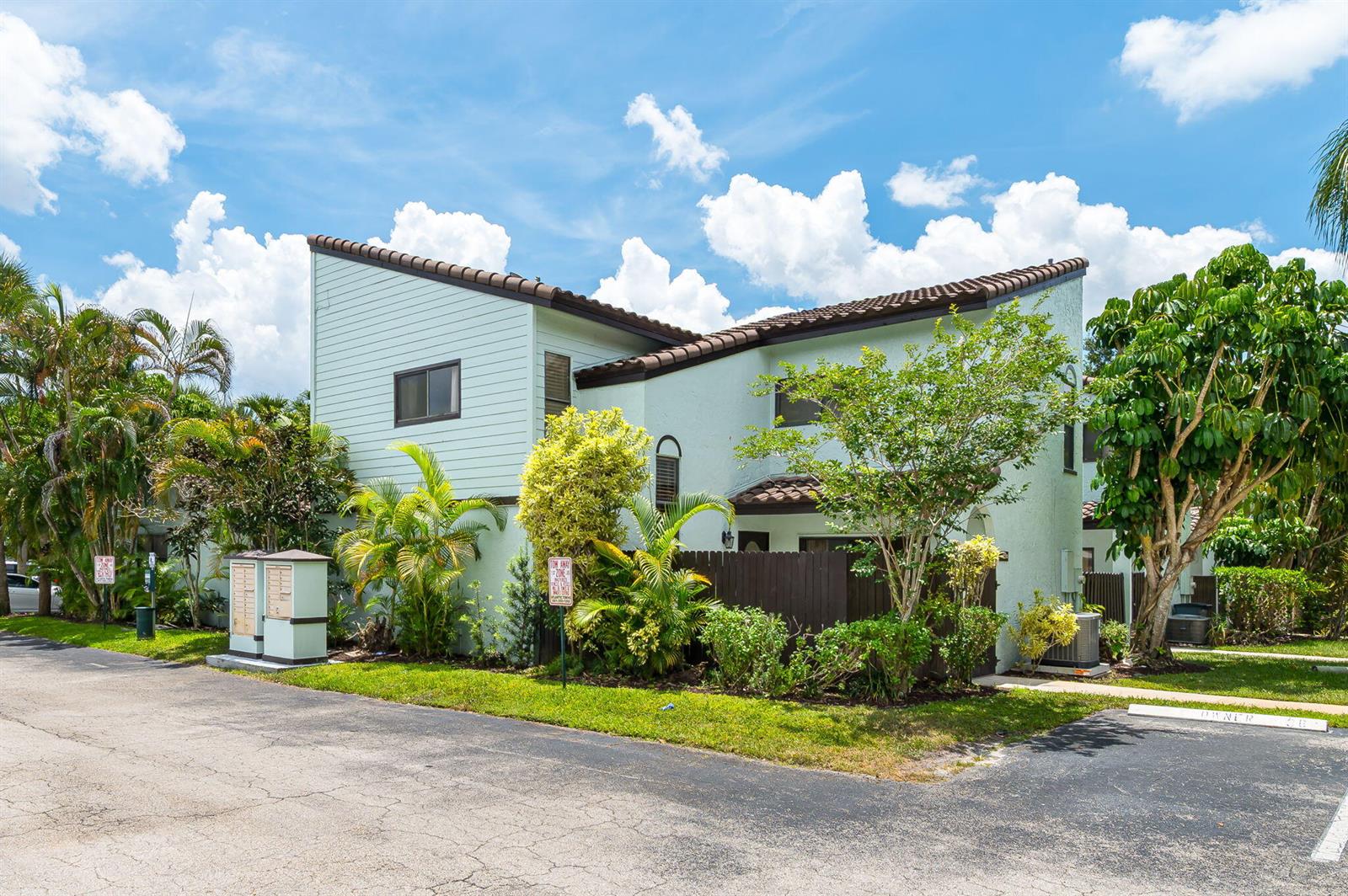 A two-story light green townhouse with a brown tiled roof and surrounding tropical landscaping — 22300 Pineapple Walk Drive, Boca Raton FL 33433, BOCA RATON, FL
