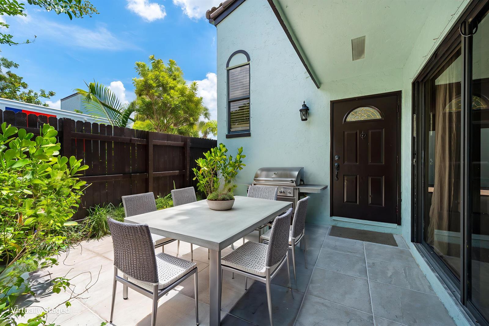 A patio features a dining table with chairs, a grill, and a dark wooden fence — 22300 Pineapple Walk Drive, Boca Raton FL 33433, BOCA RATON, FL