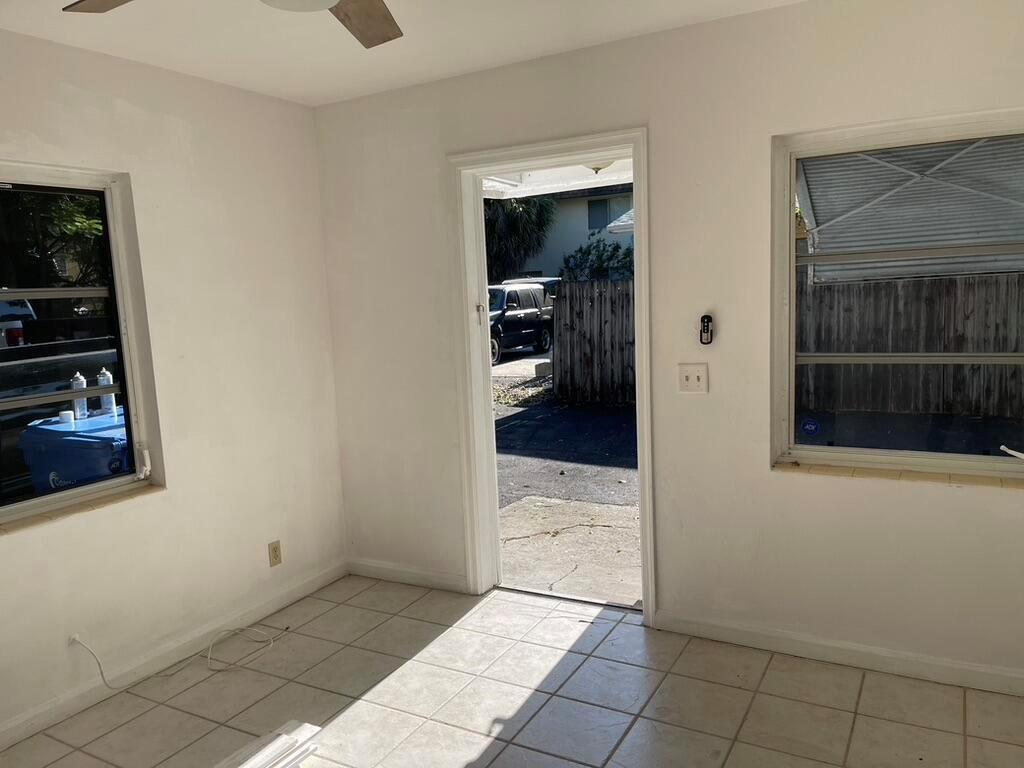 A room with white walls, tiled floors, two windows, and an open doorway leading outside — 115 E Lantana Road, Lantana FL 33462, LANTANA, FL