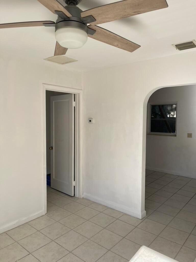 A room with white walls, tile flooring, a ceiling fan, and an arched doorway — 115 E Lantana Road, Lantana FL 33462, LANTANA, FL