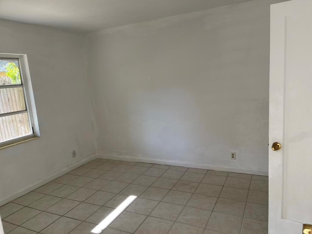 An empty room with white walls, tile flooring, and a window overlooking a wooden fence — 115 E Lantana Road, Lantana FL 33462, LANTANA, FL