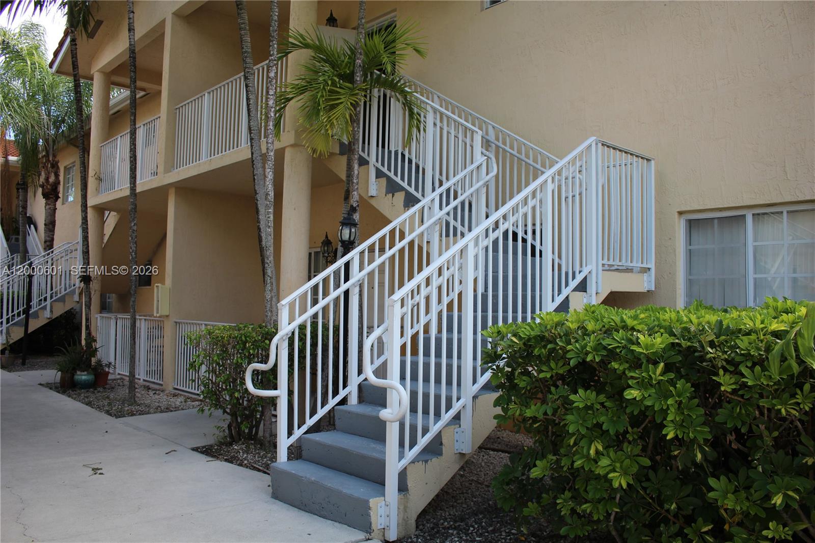 An exterior view shows a beige apartment building with white metal staircases and railings — 6962 NW 179th St # 6, Hialeah FL 33015, HIALEAH, FL