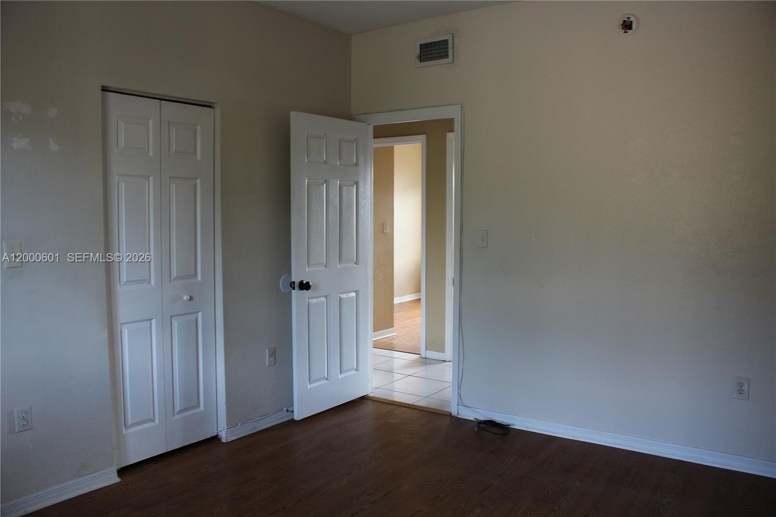 An empty bedroom features wood-look flooring, a white closet door, and an open doorway — 6962 NW 179th St # 6, Hialeah FL 33015, HIALEAH, FL