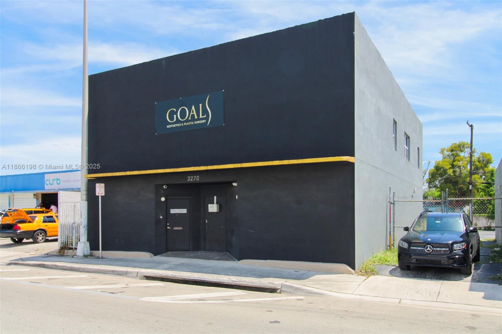 A black and gray commercial building with a sign reading GOALS Aesthetics & Plastic Surgery — 3288 NW 36th St # 3288, Miami FL 33142, MIAMI, FL