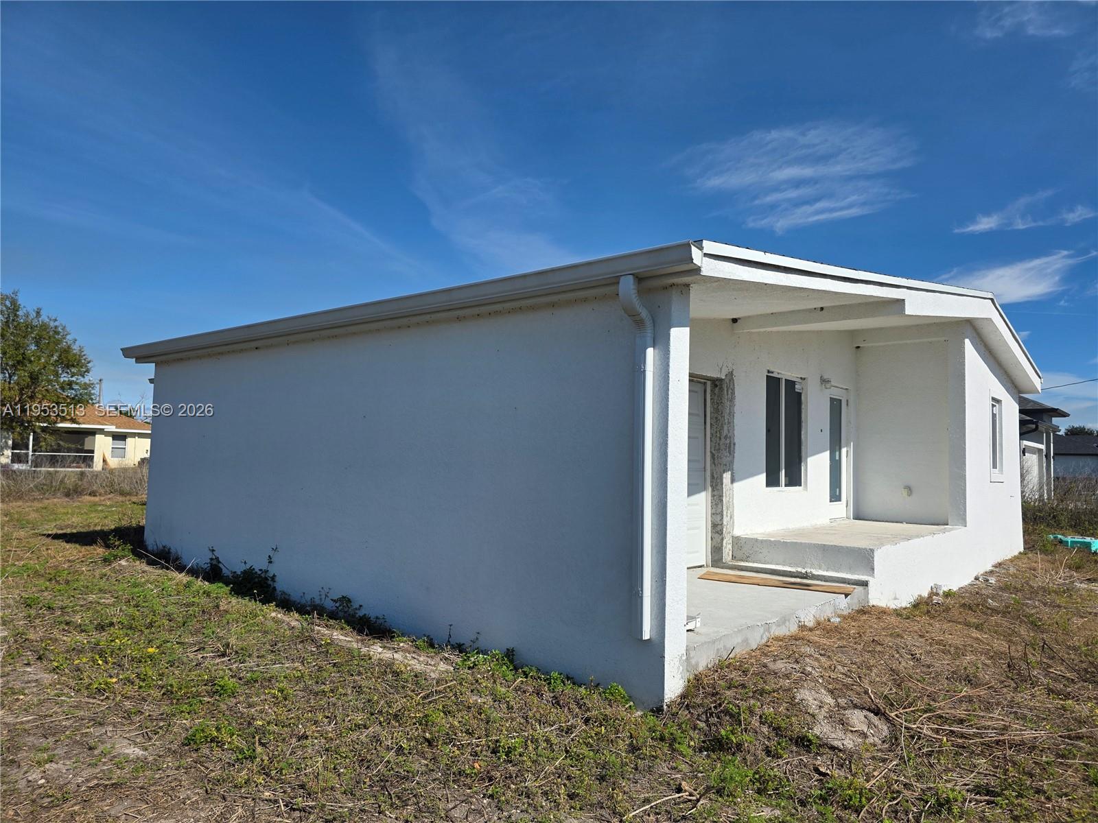 A white, single-story house with a flat roof and an open front porch — 3030 SW 39TH ST, Lehigh Acres FL 33976, LEHIGH ACRES, FL