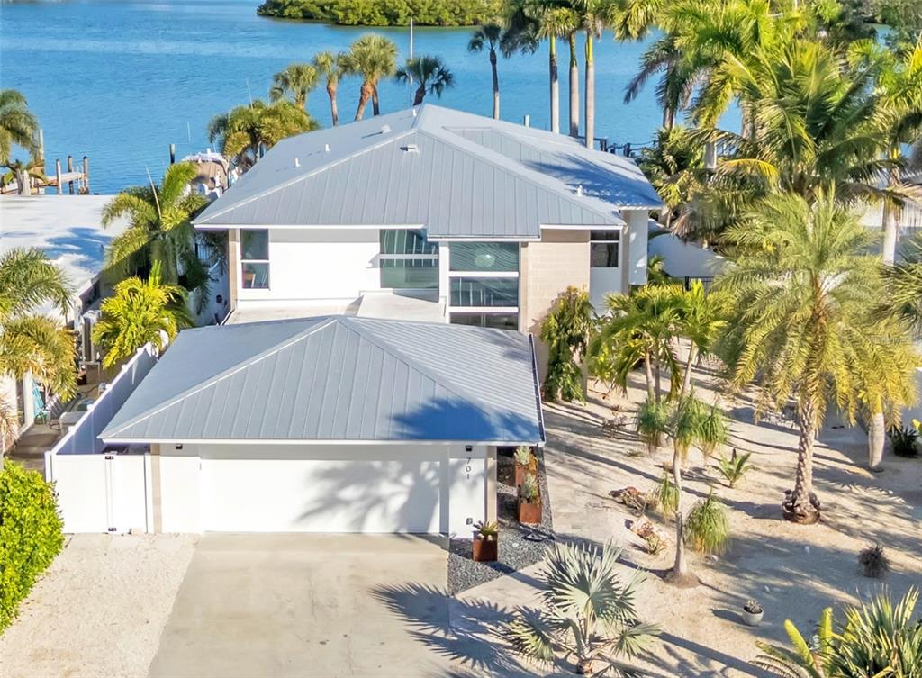 An aerial view shows a two-story house with a metal roof and attached garage — 701 TYLER DRIVE, SARASOTA, FL