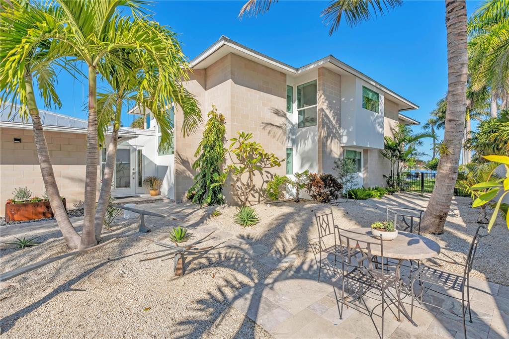 A two-story house with light-colored block walls, a gravel yard, and a patio dining set — 701 TYLER DRIVE, SARASOTA, FL