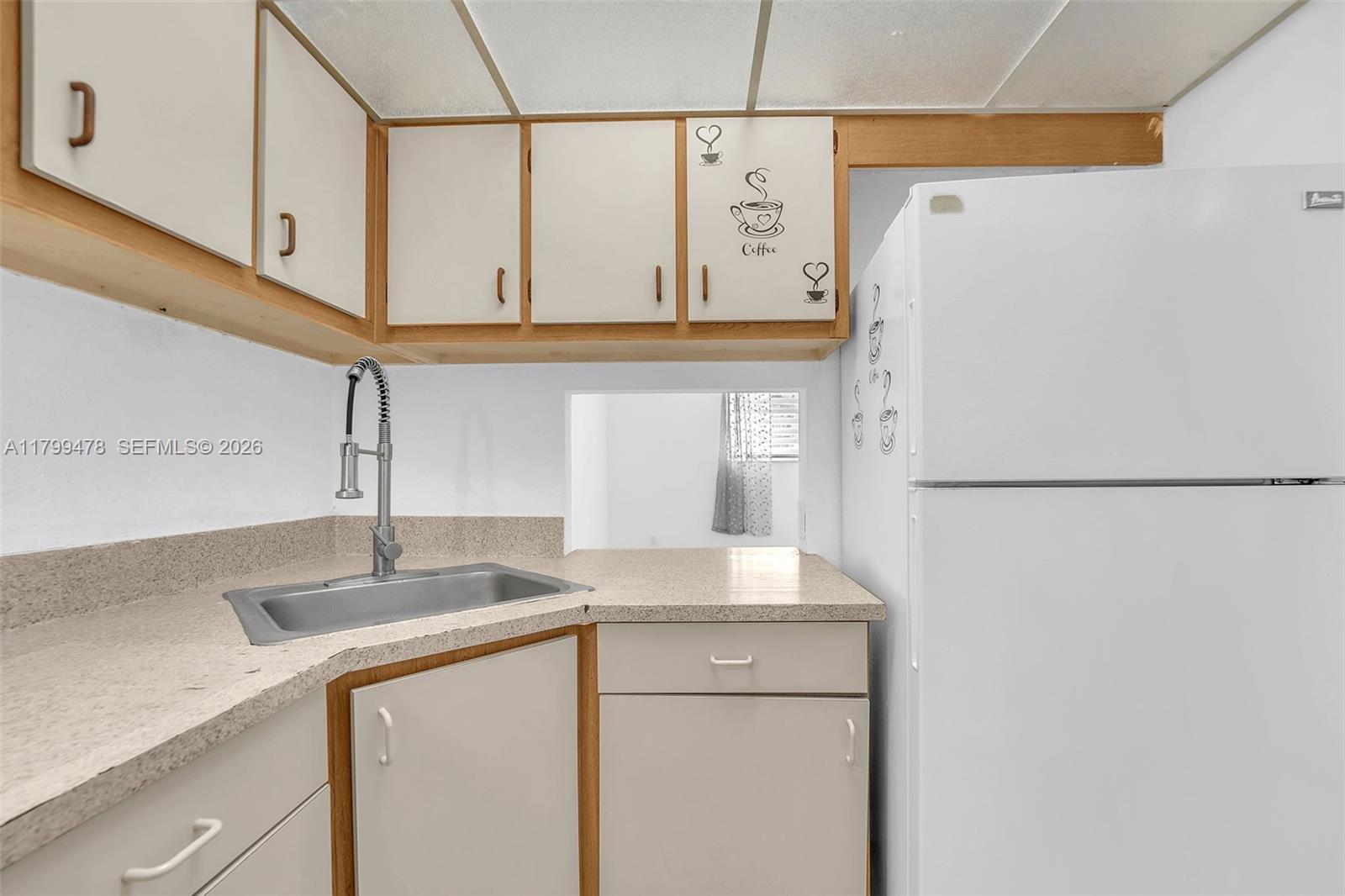 A kitchen features light-colored cabinets, a stainless steel sink, a white refrigerator, and laminate countertops — 801 NW 47th Ave # 118W, Miami FL 33126, MIAMI, FL