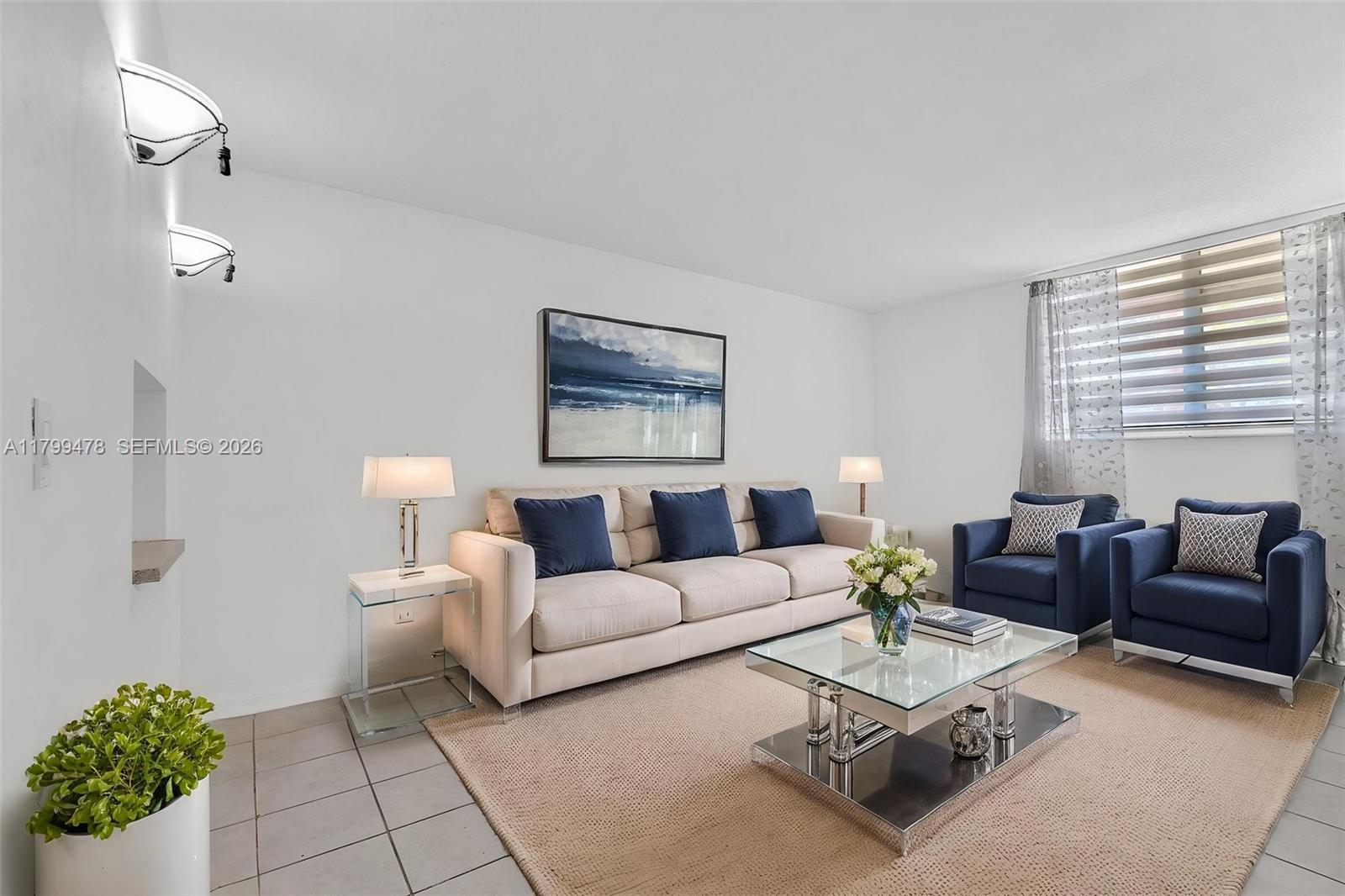 A living room features a beige sofa, two blue armchairs, and a glass coffee table — 801 NW 47th Ave # 118W, Miami FL 33126, MIAMI, FL