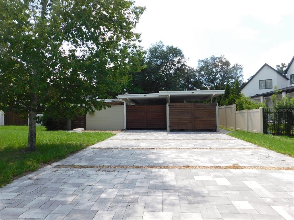 A paved driveway leads to a covered carport with wooden privacy screens and fencing — 2252 HOWARD DRIVE, WINTER PARK, FL