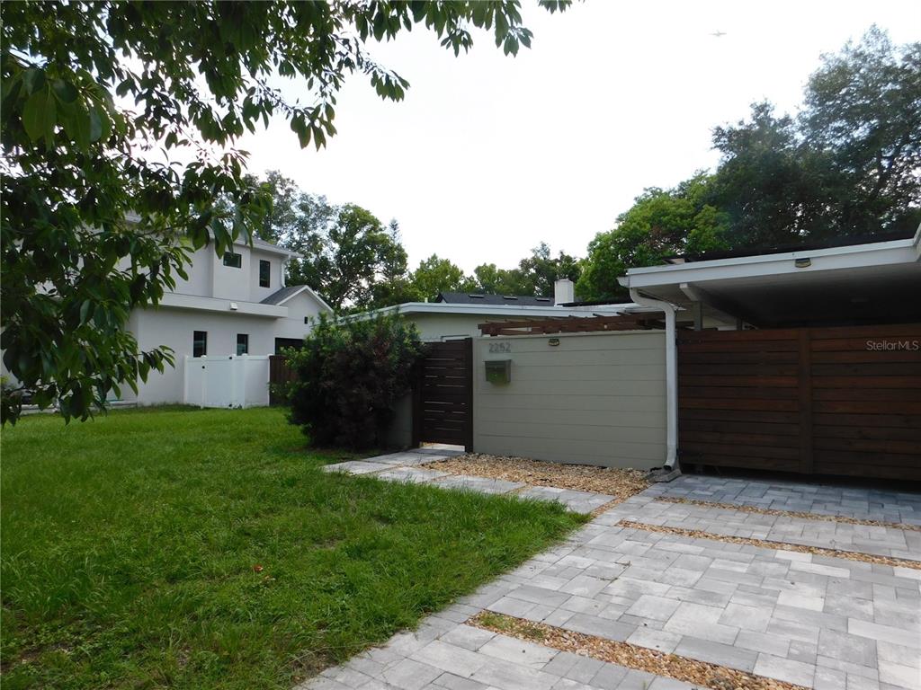 A paved driveway leads to a gated entrance and a carport with wood fencing — 2252 HOWARD DRIVE, WINTER PARK, FL