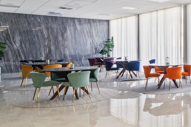 A modern dining room features multiple round tables with colorful chairs and a marble wall — 3140 S Ocean Dr # 1210, Hallandale Beach FL 33009, HALLANDALE BEACH, FL