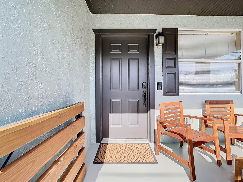 A front porch features a dark brown door, two wooden chairs, and a textured wall — 2904 SANCHEZ STREET, TAMPA, FL