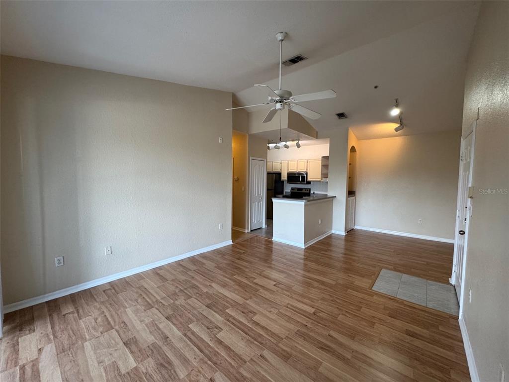 An open-concept living area features wood-look flooring, a ceiling fan, and an adjacent kitchen — 5817 LEGACY CRESCENT PLACE UNIT 302, RIVERVIEW, FL