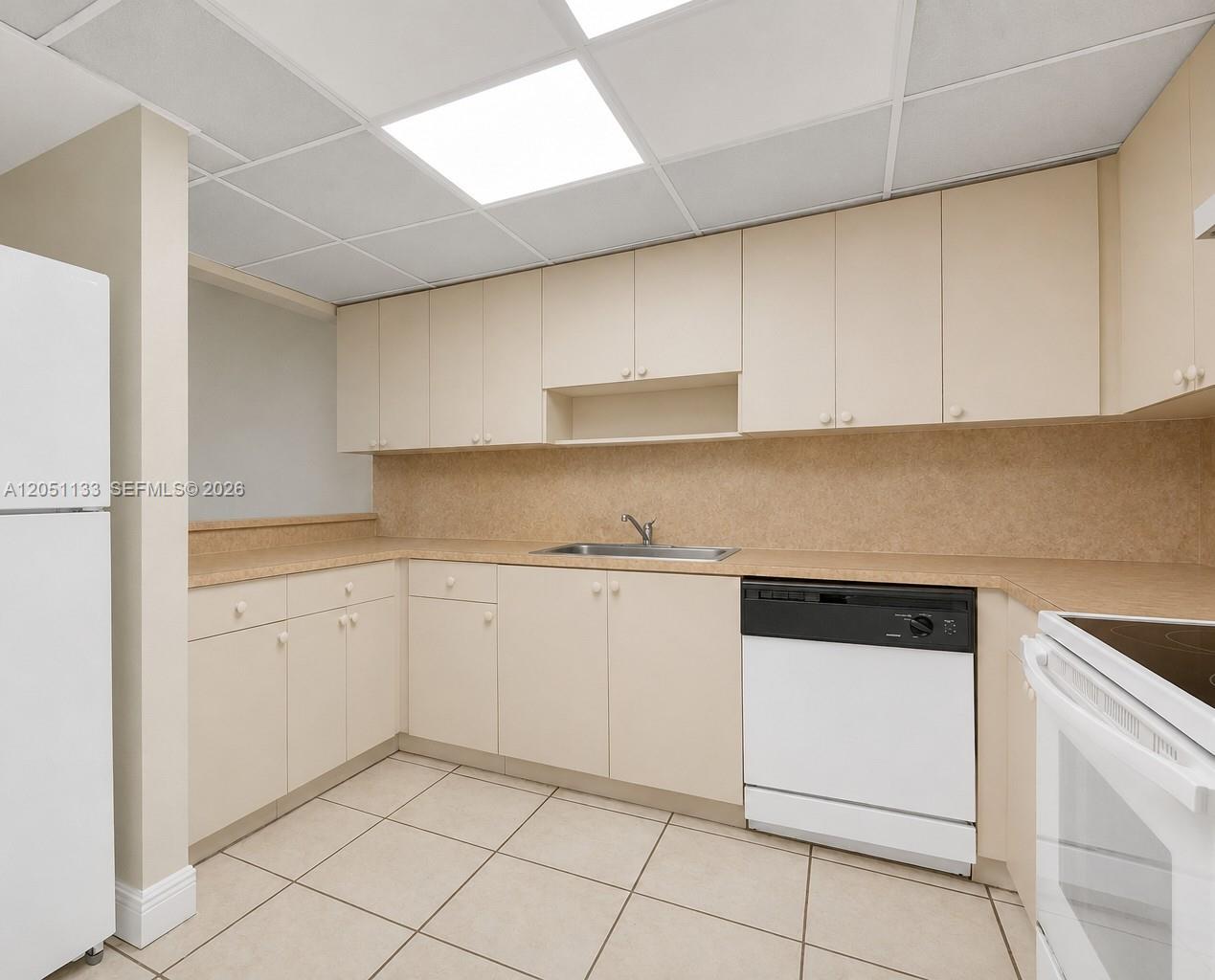 A kitchen features beige cabinets, laminate countertops, a white dishwasher, and tiled flooring — 6940 Miami Gardens Dr # 531, Hialeah FL 33015, HIALEAH, FL