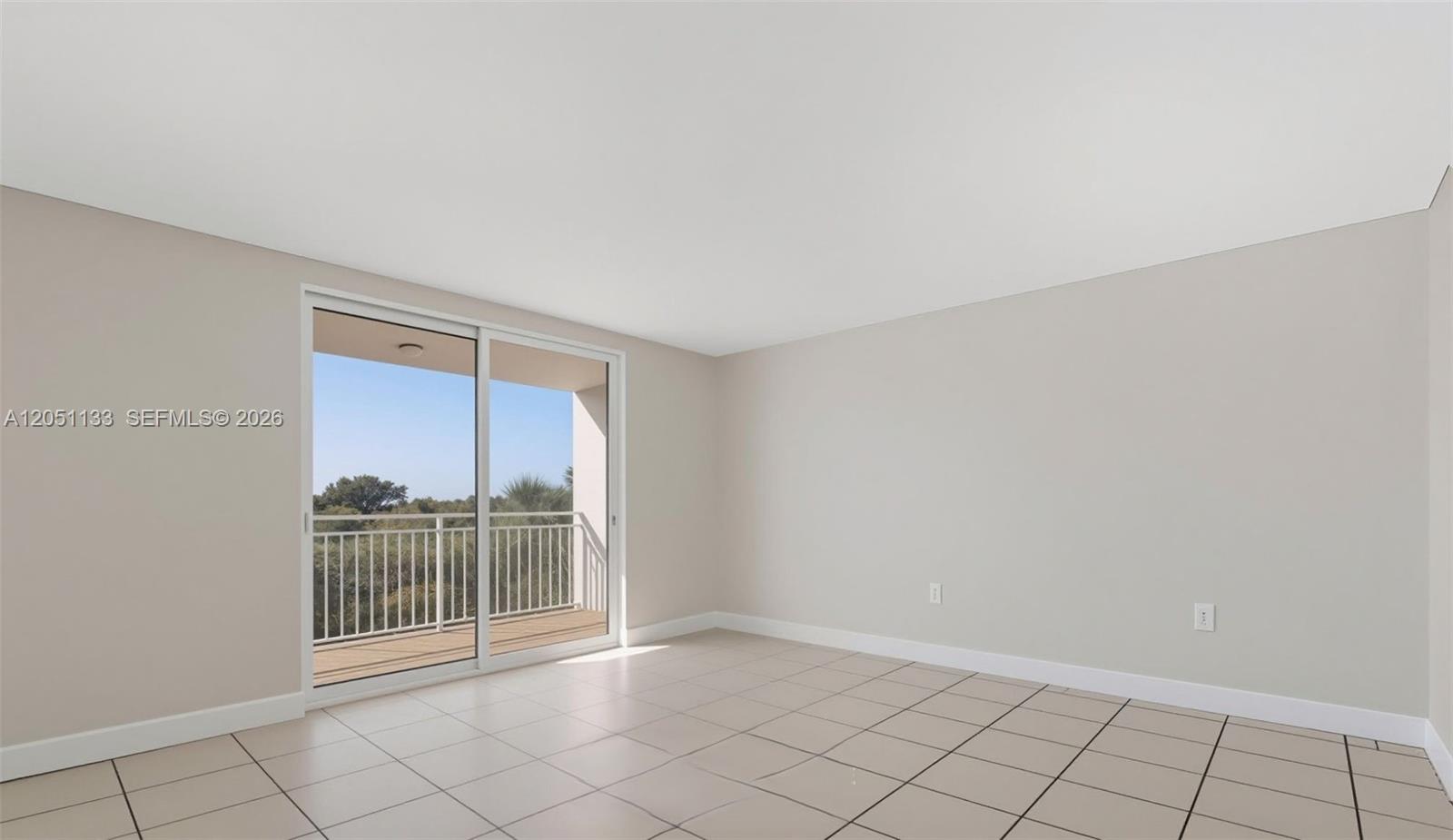 An empty room features light-colored tile flooring, beige walls, and a sliding glass door to a balcony — 6940 Miami Gardens Dr # 531, Hialeah FL 33015, HIALEAH, FL