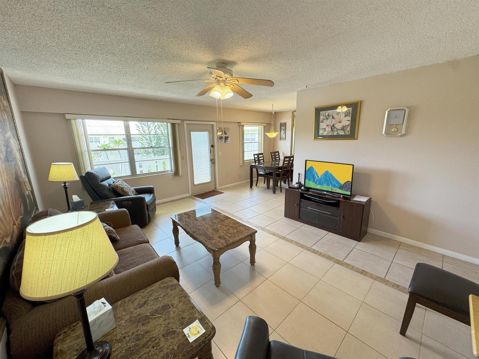 A living and dining area with tile floors, a ceiling fan, and a television console — 125 Dorset C, Boca Raton FL 33434, BOCA RATON, FL