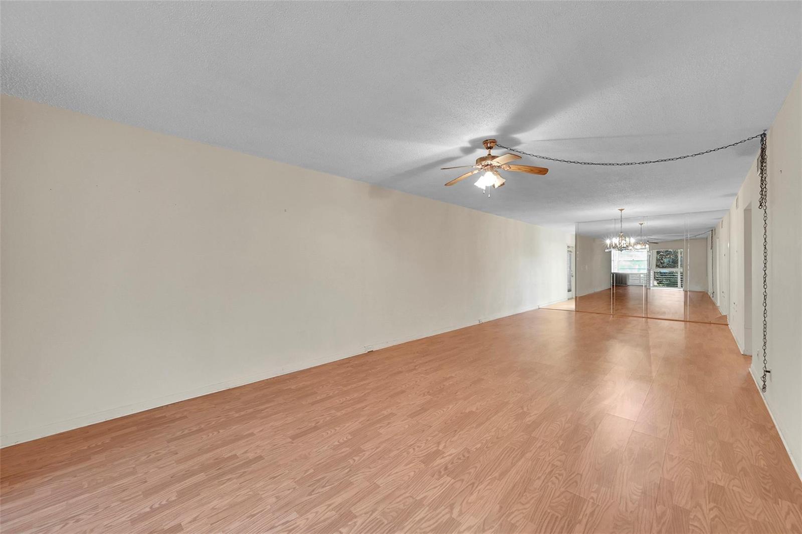 An empty room with light wood-look flooring, a ceiling fan, and mirrored wall panels — 2006 Granada Drive # A3, Coconut Creek FL 33066, COCONUT CREEK, FL