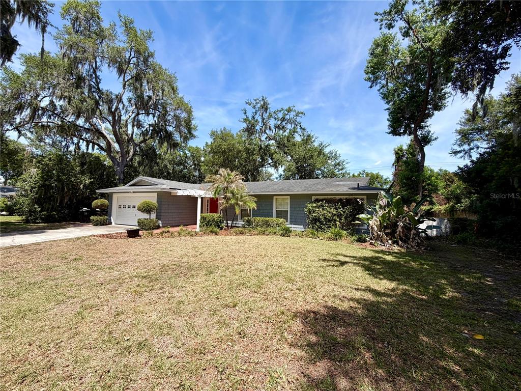 A single-story house with gray siding, a white garage door, and a large front lawn — 6322 OAK SQUARE E, LAKELAND, FL