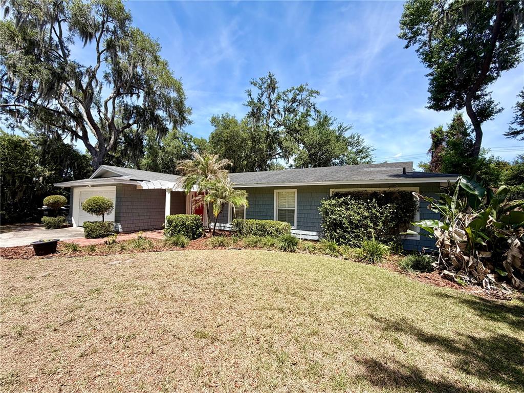 A single-story house with gray shingle siding, a white garage, and a red front door — 6322 OAK SQUARE E, LAKELAND, FL