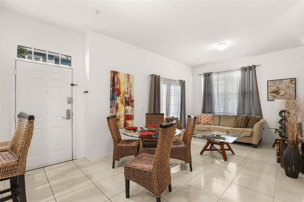 A dining and living area features tile flooring, a glass-topped table, and a beige sofa — 4005 VENETIAN BAY DRIVE UNIT 108, KISSIMMEE, FL