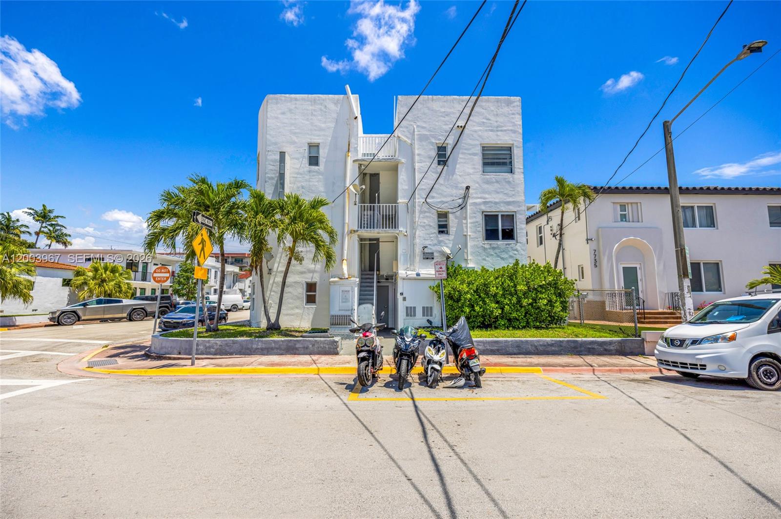 A three-story white apartment building stands behind a row of parked motorcycles and scooters — 420 78th St, Miami Beach FL 33141, MIAMI BEACH, FL