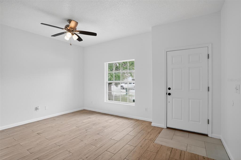 A bright room with wood-look tile flooring, a ceiling fan, and a white entry door — 1923 YELLOWFIN DRIVE, PORT ORANGE, FL