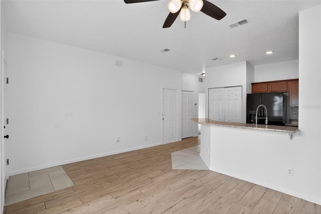 An open-concept living area features wood-look tile flooring, a breakfast bar, and white walls — 1923 YELLOWFIN DRIVE, PORT ORANGE, FL