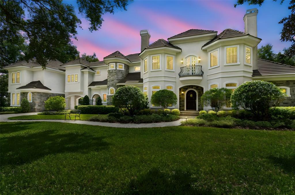 A large, two-story luxury home with a stone and stucco exterior and a landscaped lawn — 702 BERROCALES DE AVILA, TAMPA, FL