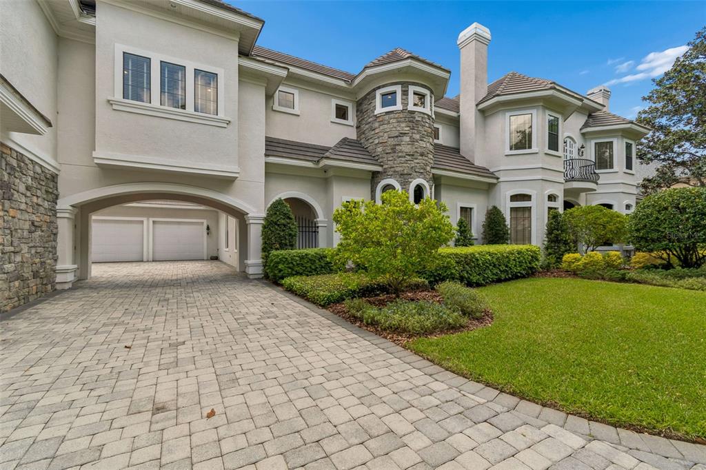 A large two-story house with a stone turret, arched garage entrance, and paved driveway — 702 BERROCALES DE AVILA, TAMPA, FL