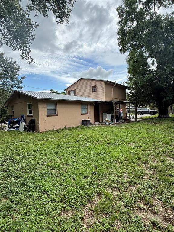 A two-story house with tan siding and a metal roof sits on a grassy lot — 4570 TRANSPORT ROAD, BARTOW, FL
