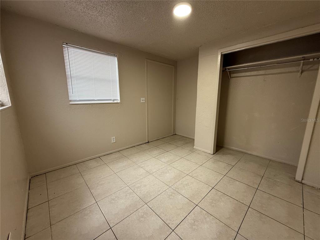 A room with light-colored tile flooring, a window with blinds, a closet, and a door — 4570 TRANSPORT ROAD, BARTOW, FL