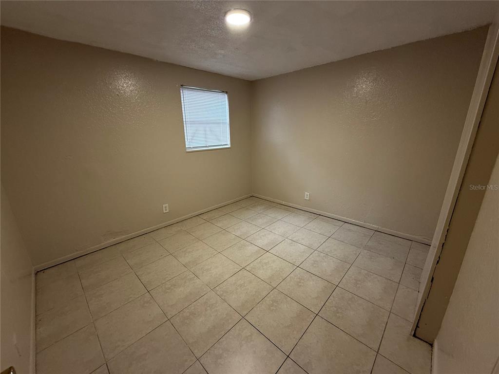 An empty room features beige walls, a single window with blinds, and light-colored floor tiles — 4570 TRANSPORT ROAD, BARTOW, FL