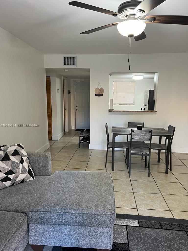 A living room with tile floors leads to a dining area and a kitchen pass-through — 18051 NW 68th Ave # K103, Hialeah FL 33015, HIALEAH, FL