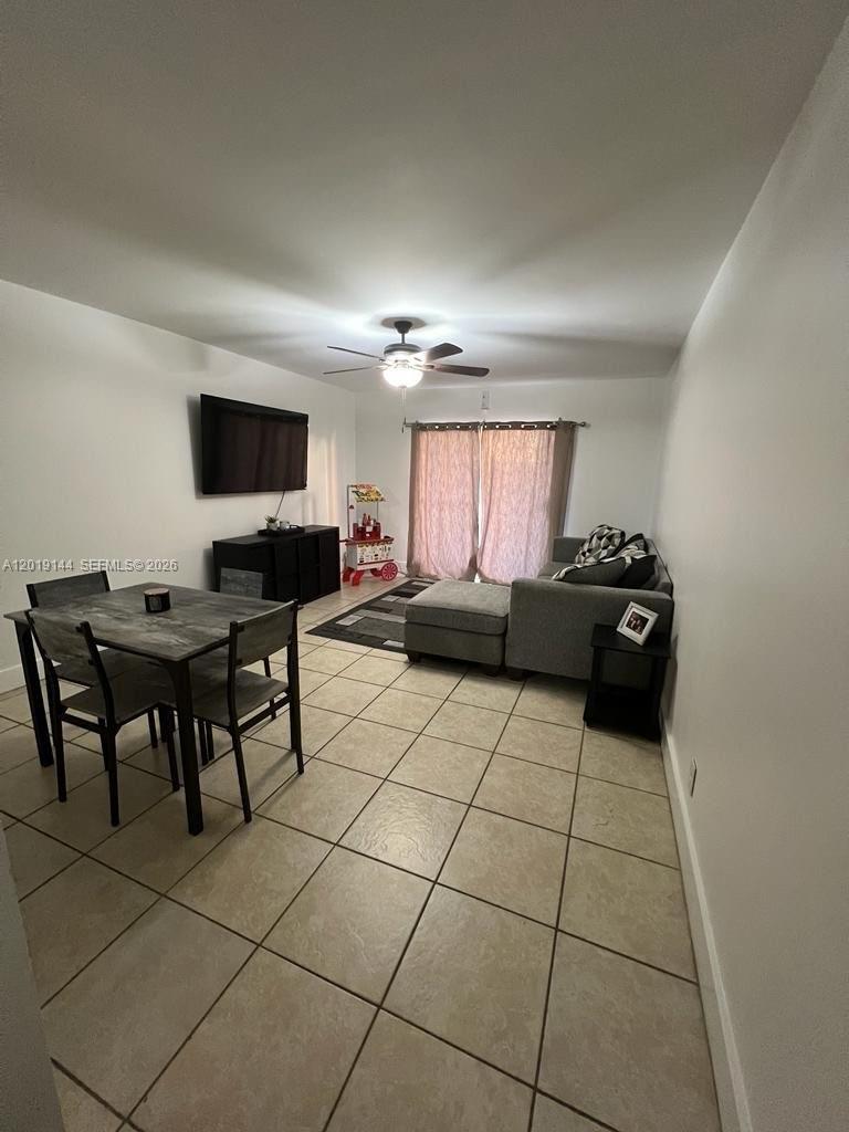 A living and dining area features tile flooring, a gray sectional sofa, and a table — 18051 NW 68th Ave # K103, Hialeah FL 33015, HIALEAH, FL