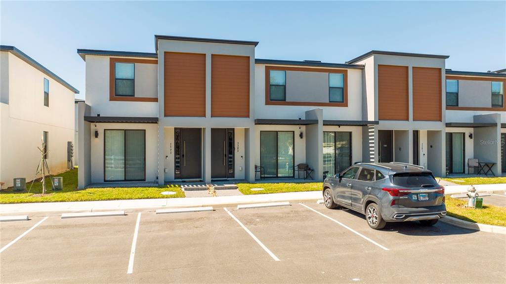 A modern two-story townhouse exterior with a gray SUV parked in the front lot — 3389 TRANQUIL TRAIL, KISSIMMEE, FL