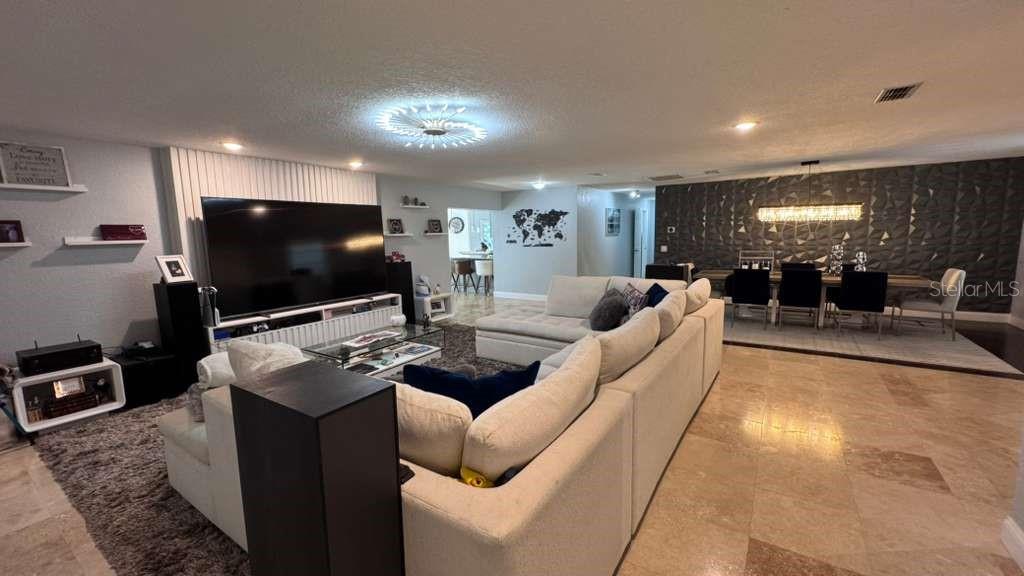 An open-concept living and dining area features a large sectional sofa, television, and tile flooring — 4627 WOODLOT COURT, ORLANDO, FL